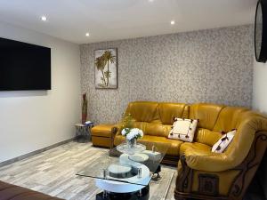 een woonkamer met een bruine leren bank en een tv bij Charmante maison à Blois - Terrasse privée - 8 pers in Blois