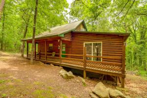 una cabaña de madera en el bosque con árboles en Rural Arkansas Vacation Rental with Wraparound Porch, en Heber Springs