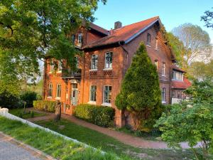 a large brick building with a tree in front of it at Pension Hessbögel in Grünendeich
