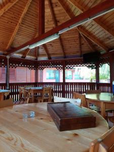 einen großen Holztisch in einem Pavillon mit Tischen und Stühlen in der Unterkunft Pensiunea La Tavi in Murighiol