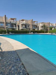 una gran piscina azul con edificios en el fondo en Exquisite Villa Rentals at North Coast Marsiellia Beach 4 Families, en El Alamein