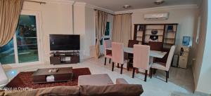 sala de estar con mesa, sillas y TV en Exquisite Villa Rentals at North Coast Marsiellia Beach 4 Families, en El Alamein