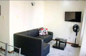 ein Wohnzimmer mit einem schwarzen Sofa und einem Flachbild-TV in der Unterkunft Apartamento Granada 2 habitaciones - 201 in Cali