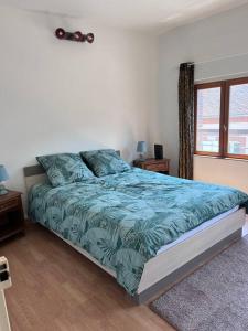 Schlafzimmer mit einem Bett mit blauer Decke in der Unterkunft Grand Appartement lumineux 2ch. Ville historique. in Verneuil d’Avre et d’Iton