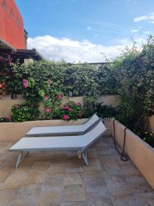 a white bench sitting on a patio with flowers at Lulamax Sardegna Olbia in Olbia