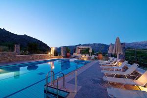 a swimming pool with white lounge chairs and umbrellas at Elia Meronas in Méronas
