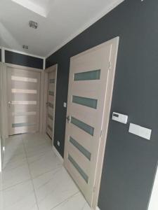 Un pasillo con dos puertas en una habitación con azulejos blancos en Apartament Brzeg, en Brzeg