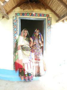 twee vrouwen in jurken in een raam bij Rann of kutch home stay in Dhordo