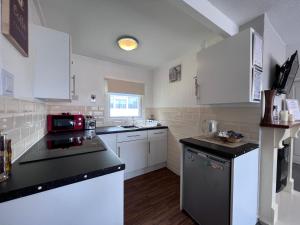 une cuisine avec des placards blancs et un comptoir noir dans l'établissement 20 Bucklands, Bideford Bay Holiday Park, à Bideford
