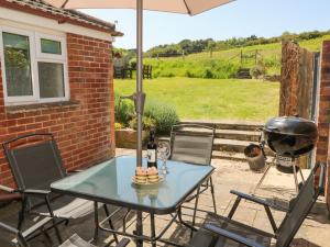 a table and chairs on a patio with a grill at Studland Cottage in Swanage