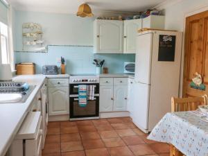 a kitchen with white cabinets and a white refrigerator at Studland Cottage in Swanage