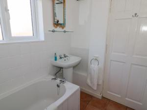 a white bathroom with a sink and a bath tub and a sink at Studland Cottage in Swanage