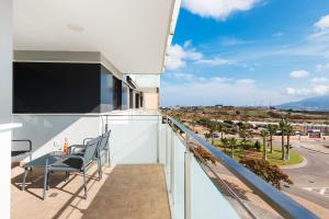 a balcony with a table and chairs and a view of a city at UNIVERSITY & TECH PARK MALAGA APARTMENT in Málaga