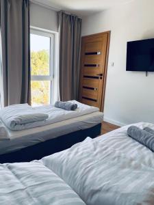 two beds in a room with a window at Apartamenty Żary in Żary