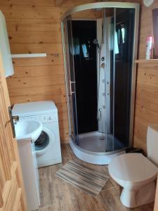 a bathroom with a shower and a washing machine at Domki na zaciszu w Rynie in Ryn