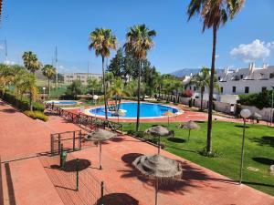 einen Pool mit Palmen und Sonnenschirmen in einem Park in der Unterkunft SUNLIVE in La Cala de Mijas