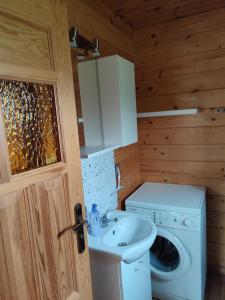a bathroom with a sink and a washing machine at Domki na zaciszu w Rynie in Ryn