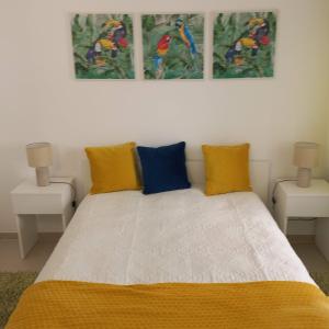 - une chambre avec un lit doté d'oreillers jaunes et bleus dans l'établissement Apartamentos Bela Vista, à Nazaré