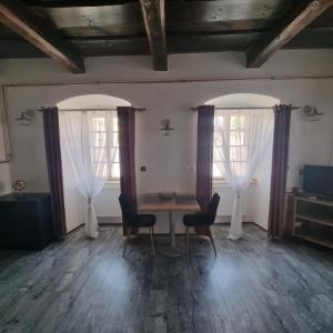 a dining room with a table and two windows at Apartmány Vila Lucia 2 in Plzeň