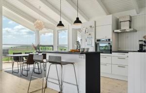 una cucina con armadi bianchi e tavolo con sedie di Gorgeous Home In Or With Kitchen a Orø