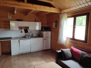 a kitchen with white cabinets and a couch in a room at Domki na zaciszu w Rynie in Ryn