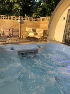una gran bañera de hidromasaje en un patio trasero con un banco en Paddock Pod - Sleeps 4 & Roofed Over Private Hot Tub en Burnfoot