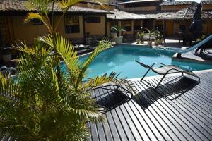 a swimming pool with a hammock and a palm tree at Nautillus Pousada in Arraial do Cabo