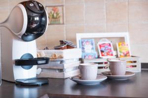 una macchina da caffè seduta su un tavolo con due tazze di La Veranda Alpago a Pieve dʼAlpago