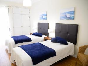 a bedroom with two beds with blue pillows at Sunset Paradise in Armação de Pêra