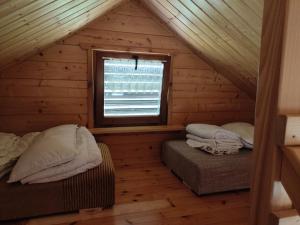 two beds in a log cabin with a window at Domki na zaciszu w Rynie in Ryn
