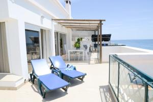 a balcony with blue chairs and a table and the ocean at Sunset Paradise in Armação de Pêra