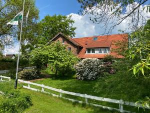 une maison avec un toit orange et un drapeau dans l'établissement Pension Hessbögel, à Grünendeich
