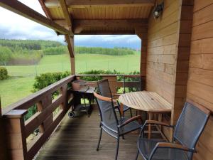 a porch with a table and chairs on a deck at Domki na zaciszu w Rynie in Ryn