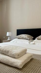 un letto con lenzuola e cuscini bianchi di The Acropolis Cave Apartment ad Atene
