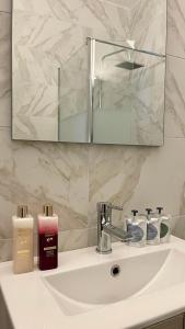 a bathroom sink with a mirror and a bottle of soap at The Acropolis Cave Apartment in Athens +15 photos