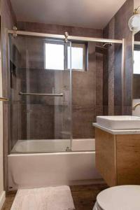 a bathroom with a shower and a tub and a sink at Fireweed Gardens in Roger’s Park in Anchorage