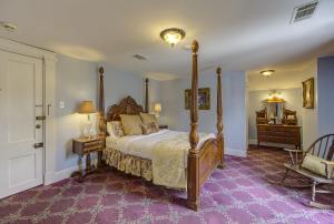 a bedroom with a canopy bed and a purple carpet at The Inn at Cedar Grove in Vicksburg
