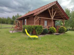 a yellow chair in front of a small house at Domki na zaciszu w Rynie in Ryn