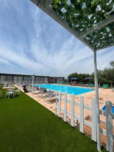 a large swimming pool with chairs and a white fence at agriturismo borgo baldassarre in Cellole