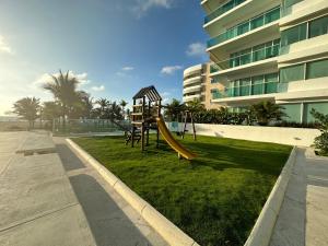 een speeltuin met een glijbaan in een grasveld naast een gebouw bij Espectacular apto en Cartagena con salida directa a la playa in Cartagena