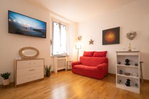 a living room with a red chair and a tv at PortaTorre Suite, a Charming apartment in the Heart of Como, Free Private Parking, Air Conditioning & More! in Como
