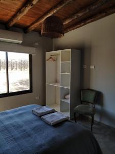 sypialnia z łóżkiem, krzesłem i oknem w obiekcie Finca La Clementina w mieście Tunuyán