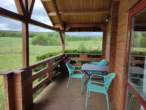 a wooden porch with a table and chairs on it at Domki na zaciszu w Rynie in Ryn