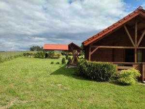 a barn in a field next to a fence at Domki na zaciszu w Rynie in Ryn