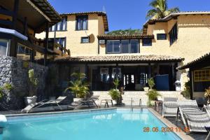 a villa with a swimming pool in front of a building at Nautillus Pousada in Arraial do Cabo