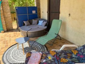 a patio with a couch and a chair and a table at L’échappée de Vallon in Vallon-Pont-dʼArc