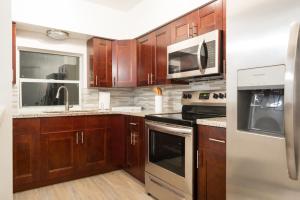 una cocina con armarios de madera y electrodomésticos de acero inoxidable en New Star Suite Two en North Miami Beach