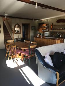 ein Wohnzimmer mit einem Sofa, einem Tisch und Stühlen in der Unterkunft Kate’s Cottage 