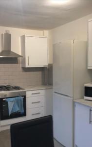 uma cozinha com armários brancos e um frigorífico branco em Falcon Drive Room 1 em Oldham
