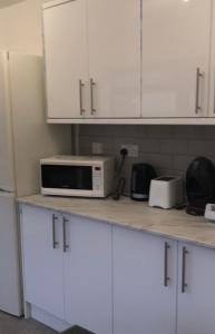 a kitchen with white cabinets and a microwave on a counter at Falcon Drive Room 1 in Oldham